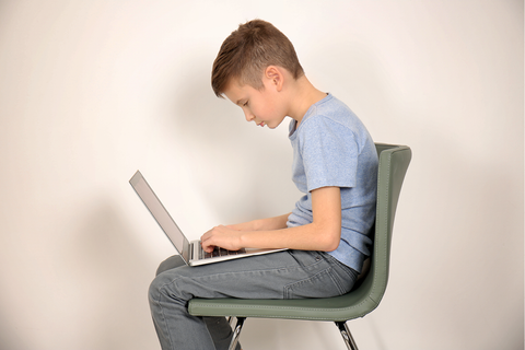 Afbeelding van een kind dat voorovergebogen op een stoel zit met een laptop op zijn schoot